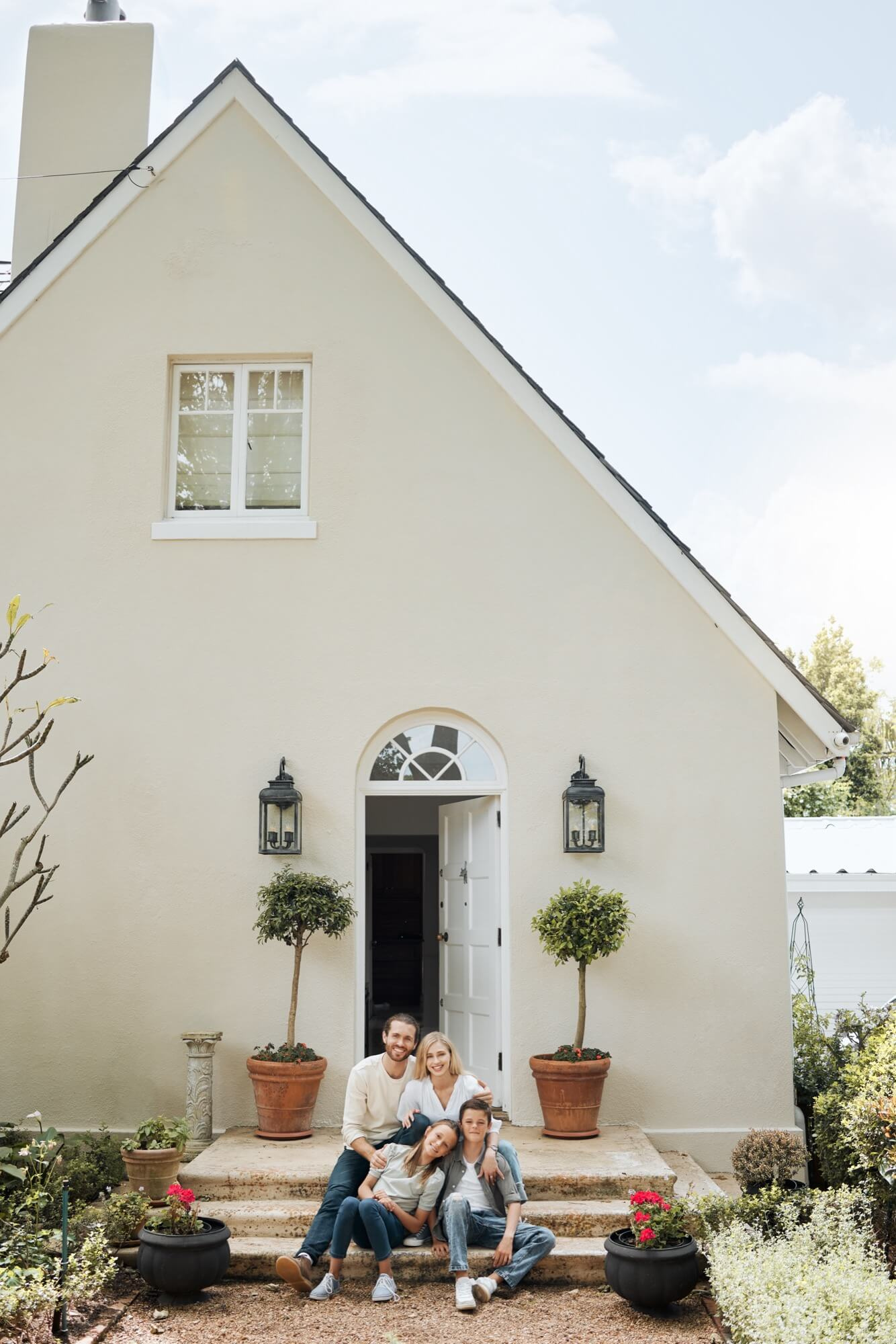 Family sitting in front of their house with bright plaster facade after facade renovation.